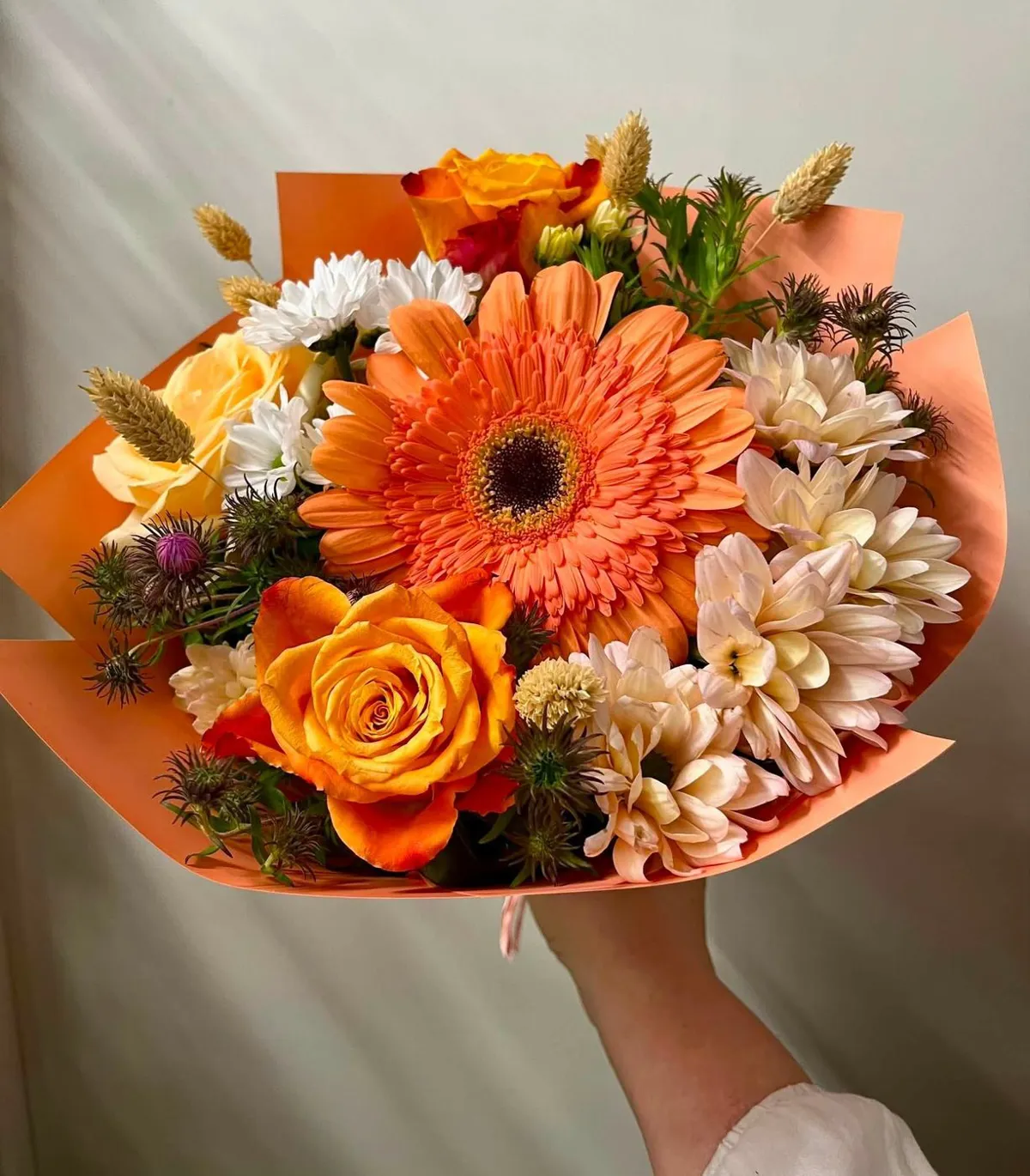 Oranžs pušķis ar lielu gerberu un rozēm oranžā papīrā